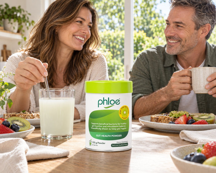 Couple at a sunny breakfast table with a glass of Phloe Gut Health Powder mixed in water
