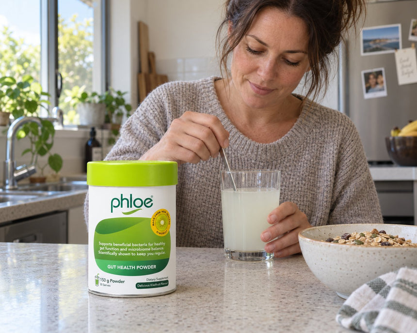 Woman stirring Phloe Gut Health Powder into a glass of water at breakfast